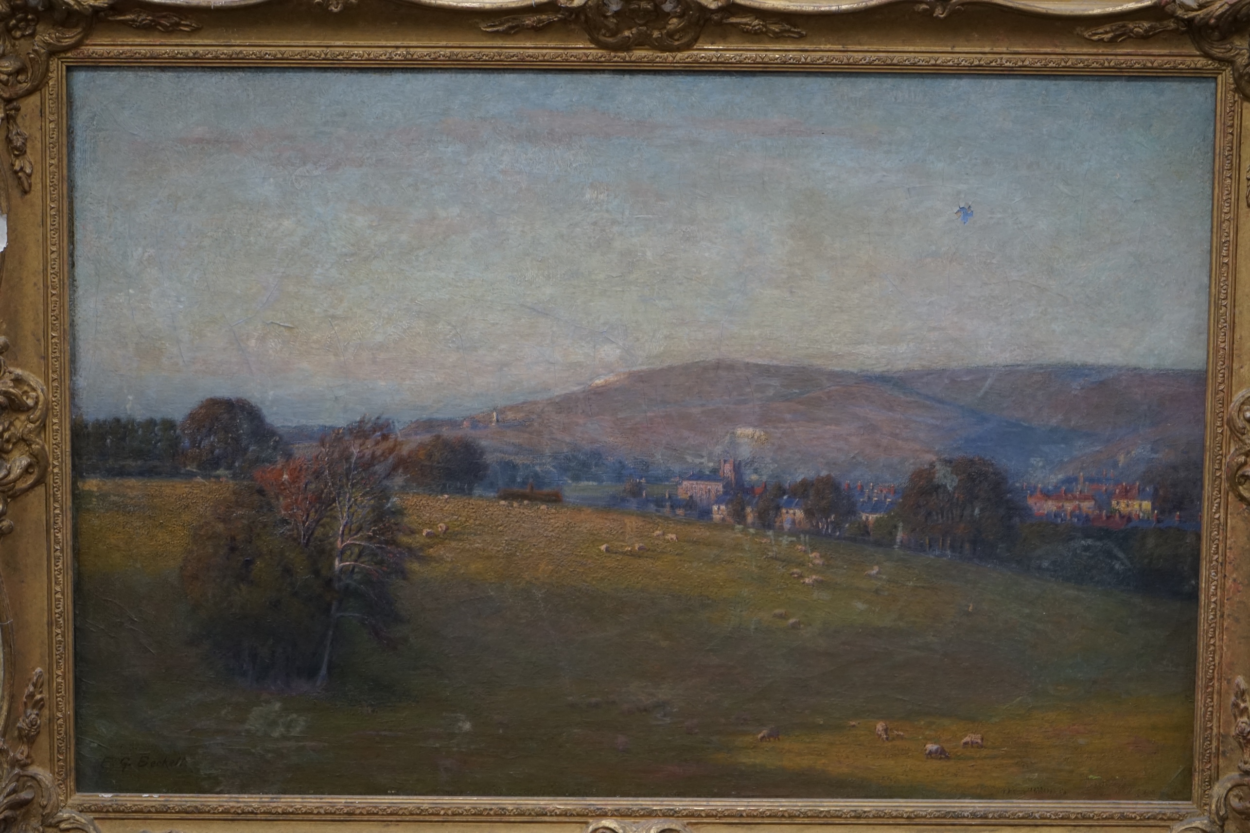 E G Beckett, oil on canvas, Extensive landscape with town before hills, signed, 48 x 75cm, ornate gilt framed. Condition - poor